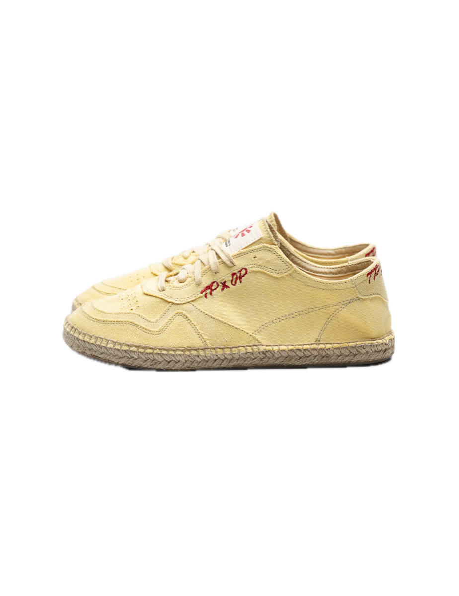 A pale yellow cotton canvas espadrille sneaker on a braided jute sole.